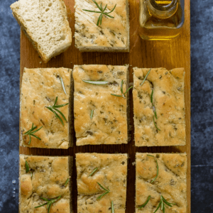 bread on a chopping board with a bottle of olive oil