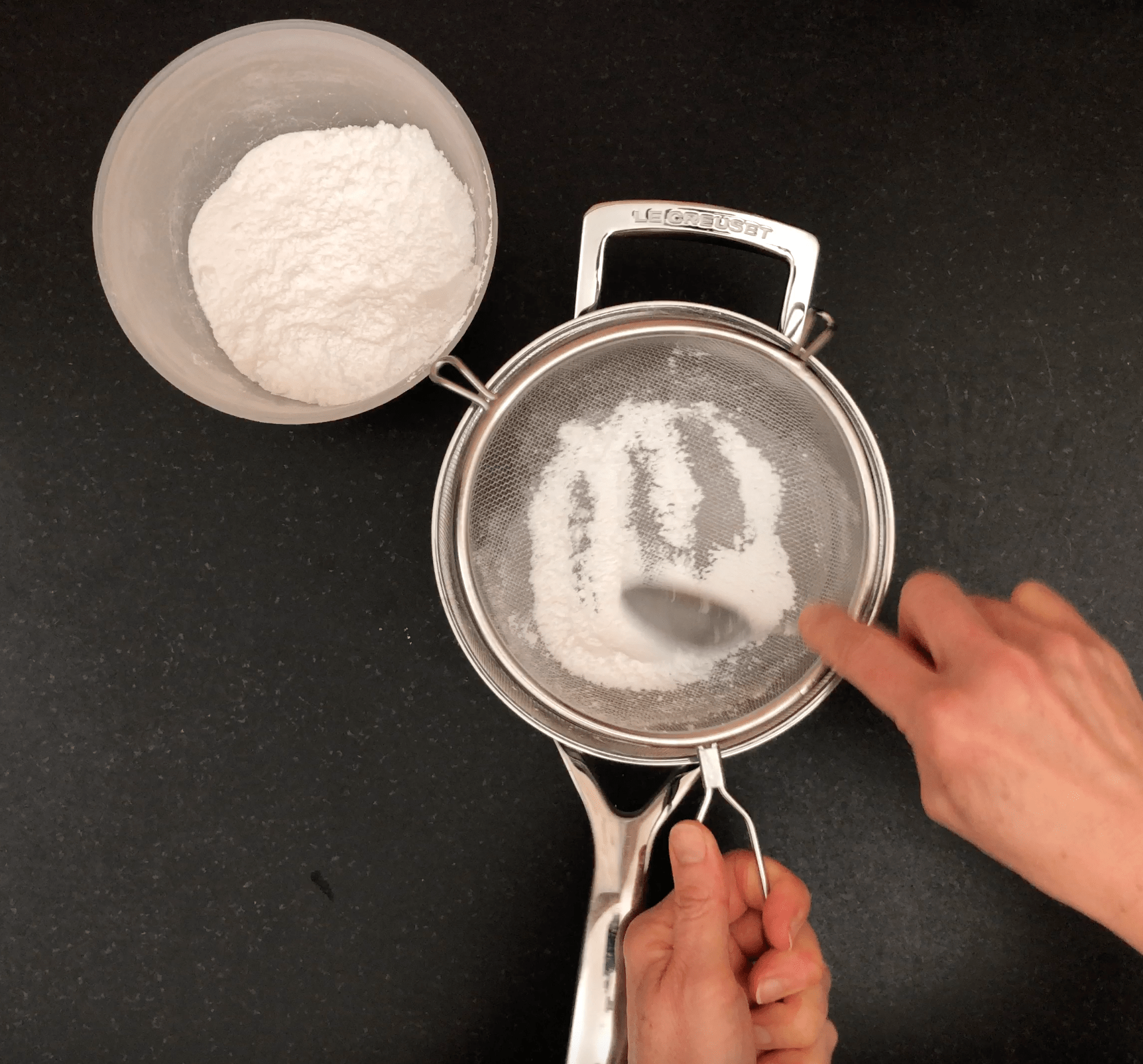Sieving icing sugar into saucepan