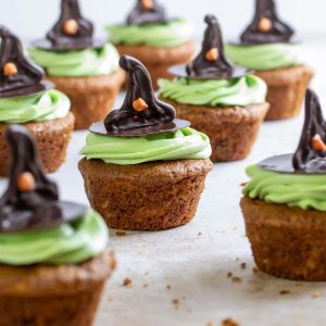 Cupcakes decorated with green frosting and chocolate witches hat with orange dot