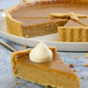 Slice of pumpkin pie with cream on a silver palette knife