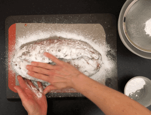 Rubbing icing sugar onto loaf of bread