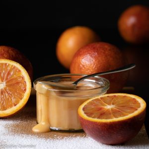 Blood orange curd dripping down a jar
